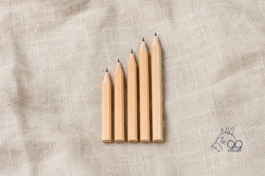 本色亚麻布上五支削好的木铅笔按长短排成阶梯，正俯拍